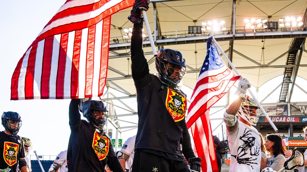 The Green Berets and Navy SEALs carry flags onto the field