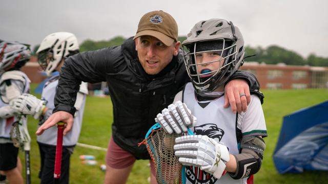 A coach with a youth boys' lacrosse player